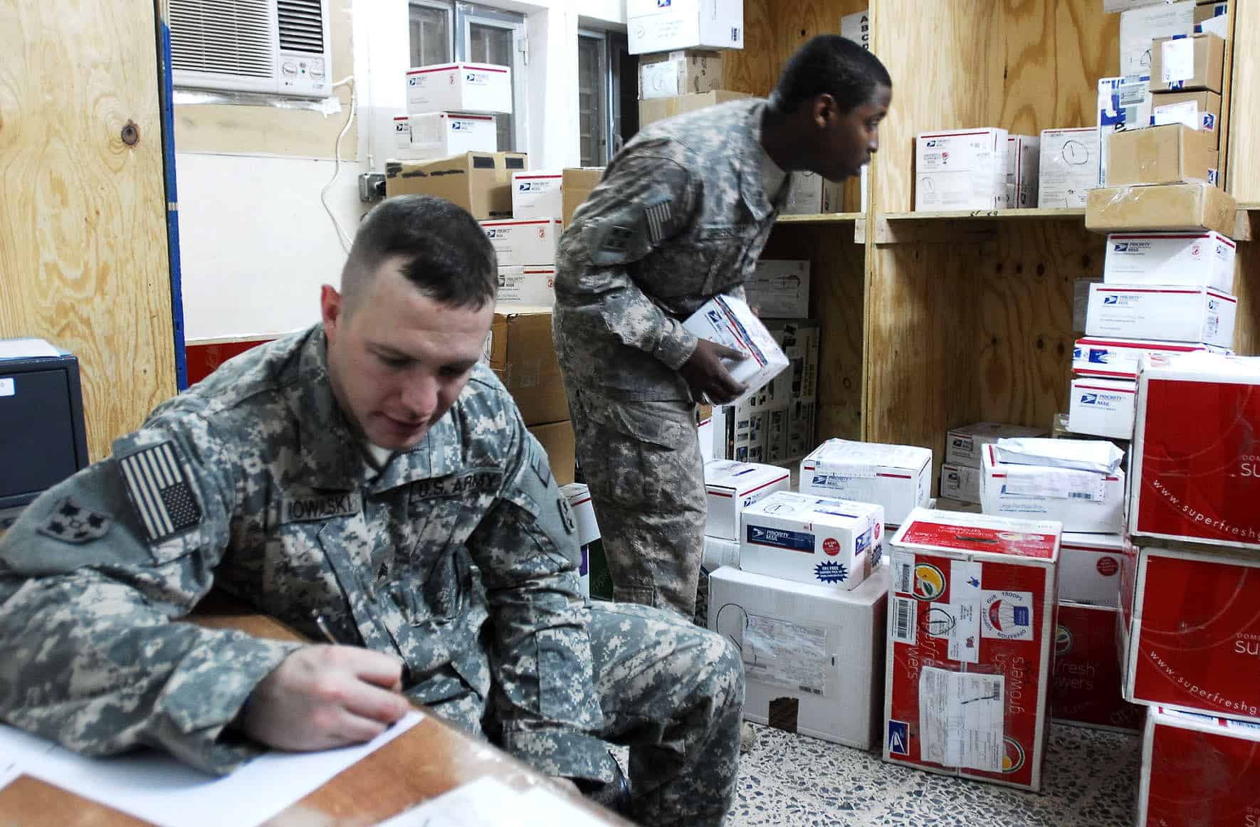 Two soldiers process mail in a US Army Forward Operating Base Mailroom